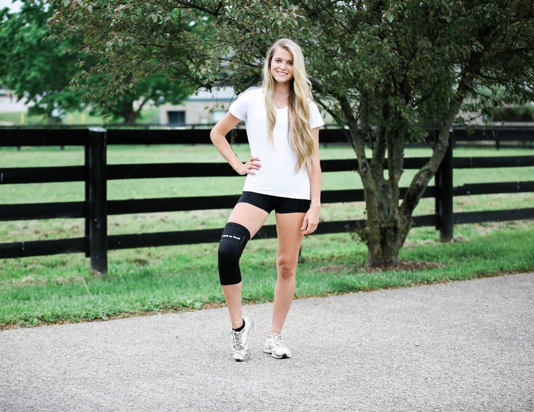 women wearing a white polo shirt, black shorts and a knee brace