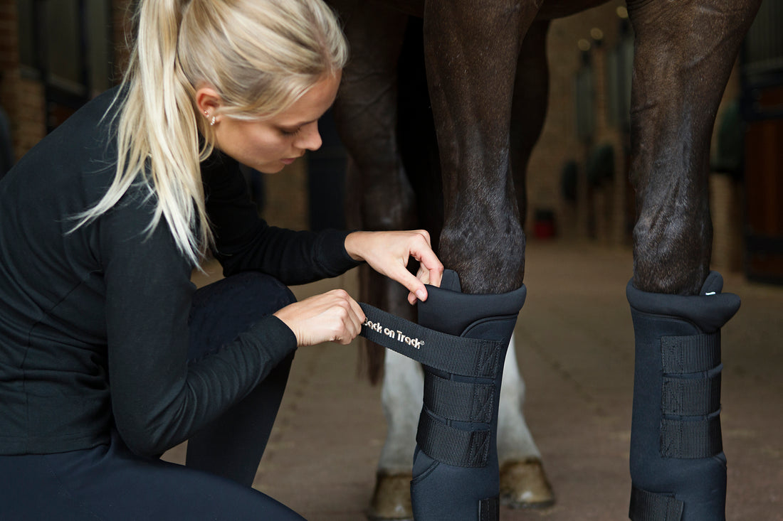 blonde lady putting a quick wrap on a horse