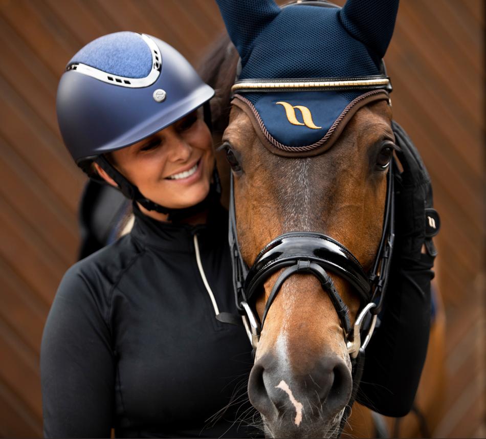 lady wearing blue helmet and bay horse wearing a blue bonnet