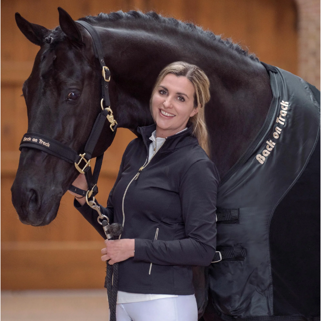 black horse wearing black werano halter and black mesh rug with a blonde lady holding the lead rope 