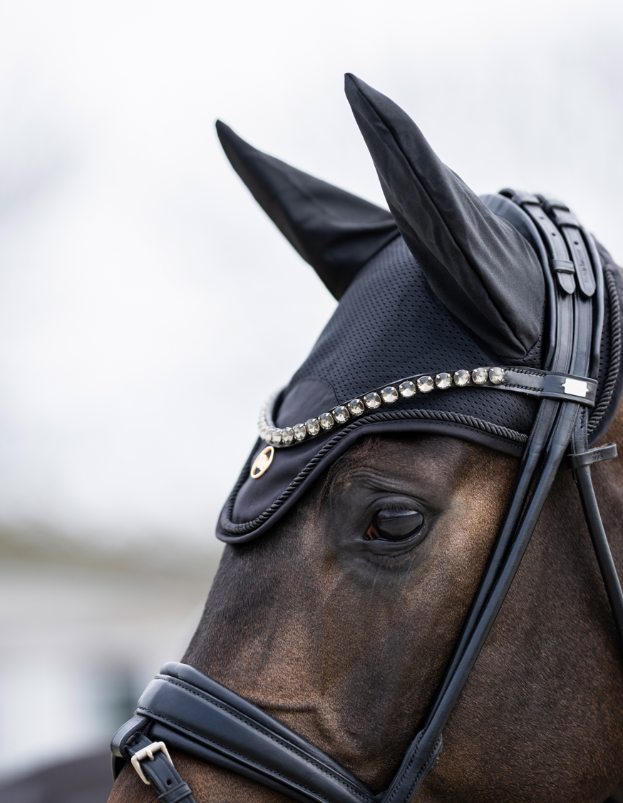 black horse bonnet with a matte gold BOT emblem and black piping - being worn by a bay horse