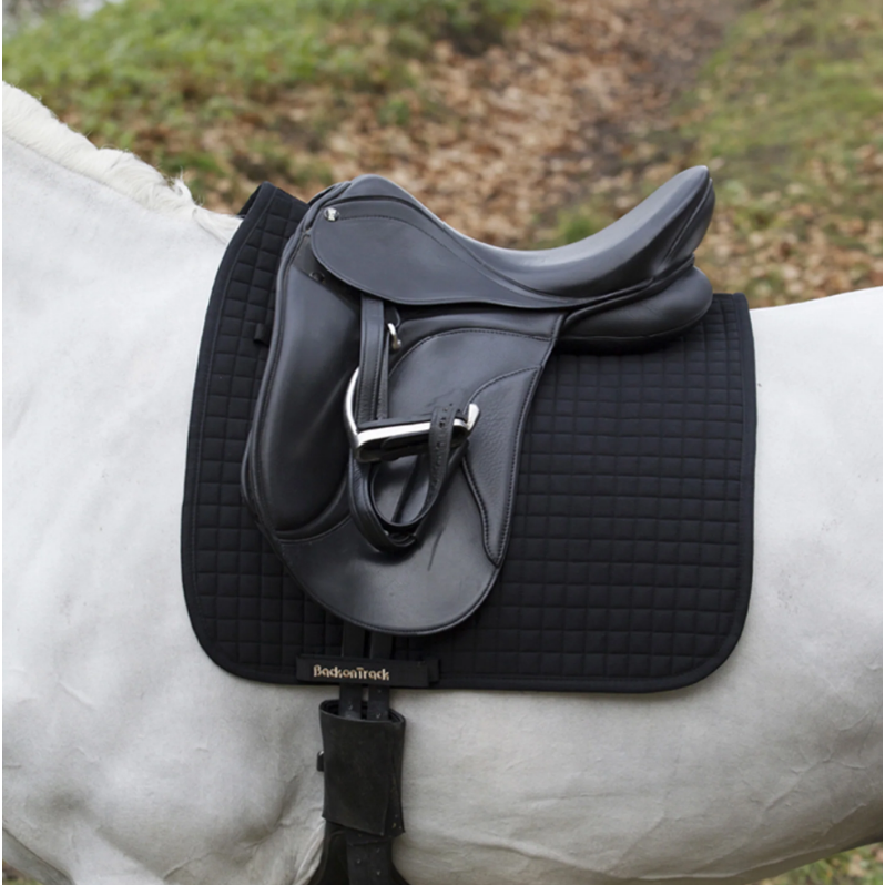 black dressage saddle pad with gold BOT and metal logo tag under saddle on a white horse