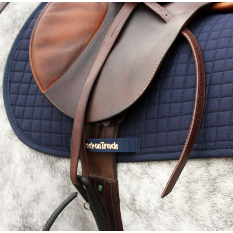 navy saddle pad under saddle on grey horse